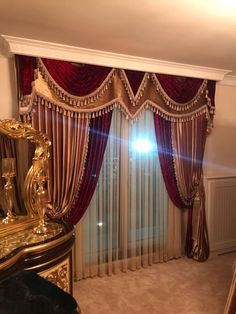 a bedroom with a large window covered in red drapes and gold trimmings