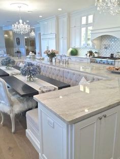 a large kitchen with white cabinets and marble counter tops