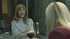 a woman sitting at a table with a glass of wine