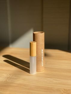 an empty roll - on bottle sitting on top of a wooden table next to a cardboard tube