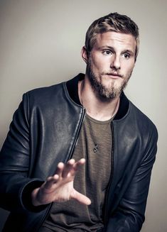 a man wearing a black leather jacket and holding his hands out in front of him