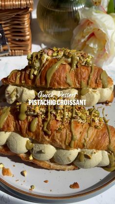 two pieces of bread covered in green sauce sitting on a white plate next to flowers