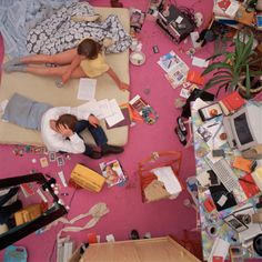 two people are sitting on a bed surrounded by clutter