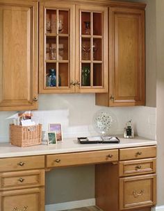 a kitchen with wooden cabinets and white counter tops, including a glass door cabinet above the sink