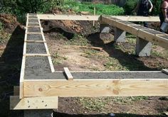 two men are working on building a raised garden bed in the yard with wood and concrete