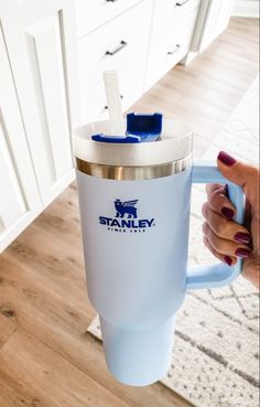 a woman holding a blue and white coffee cup in her hand with the stanley logo on it