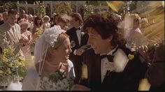 a bride and groom standing in front of a large group of people wearing tuxedos