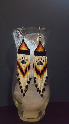 a pair of beaded earrings sitting on top of a glass vase