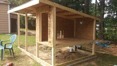 a chicken coop built into the side of a yard with chairs around it and trees in the background