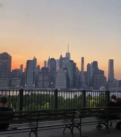 people are sitting on benches overlooking the city