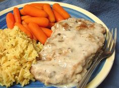 a blue plate topped with meat covered in gravy next to carrots and rice