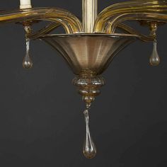 a chandelier with three candles hanging from it's sides and drops of water on the bottom