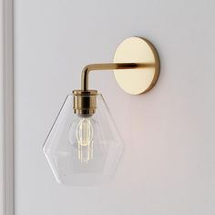 a light that is on the wall next to a white door with a gold handle