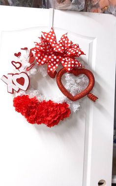 a red and white heart wreath hanging on a door