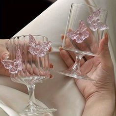 two hands holding wine glasses with pink butterflies on them