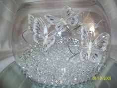 a glass bowl filled with lots of white butterflies