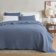 a bed with a blue comforter and pillows on top of it in a room