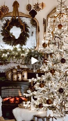 a white christmas tree in front of a fireplace with ornaments on it and a mirror