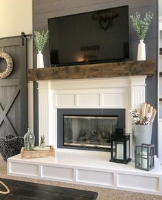 a fireplace with a flat screen tv above it and other decorations on the mantles