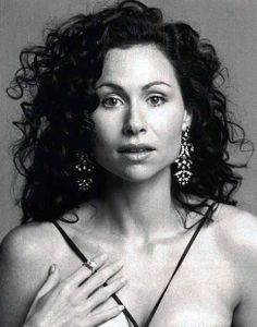 a black and white photo of a woman with large earrings on her shoulder, looking at the camera