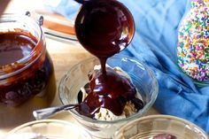 chocolate sauce being drizzled over ice cream in small bowls with sprinkles