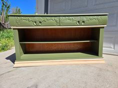 a green shelf sitting on top of a cement floor next to a garage door with flowers painted on it