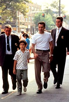 two men and a little boy walking down the street with other people on either side