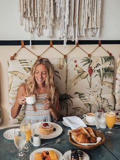 a woman sitting at a table with food and drinks