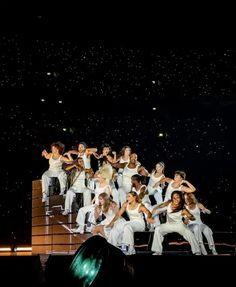 a group of people standing on top of a stage with their arms in the air