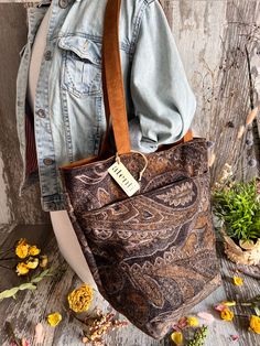 Our Chester is a faded black velvet with a rich printed design. Warm gold and brown tones mix elegance and earthy, the darker color way. The Bon Bucket has an interior zipper pocket, two large interior open pockets, and two open exterior pockets. This bag has feet, two 26" straps, two exterior pockets, and a magnetic closure. Dimension: 13.00"W x 14.00"H x 6.50"D