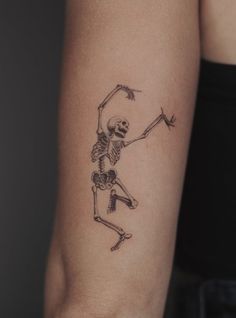 a woman's arm with a skeleton and arrow tattoo on the left side of her arm