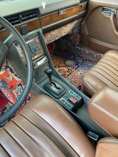 The inside of a car. The floors are decorated with persian rugs. The seats and car door are brown. The steering wheel is black. Auto Retro, Classy Cars, Old Car, Future Car, Cute Cars, Retro Cars