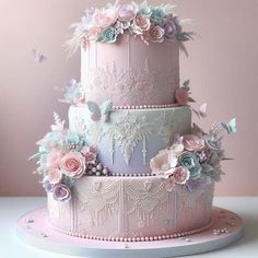 a three tiered cake with pink and blue flowers on the top, surrounded by butterflies