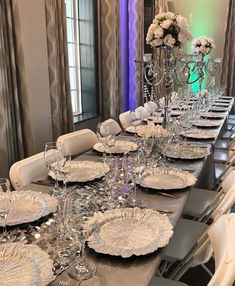 a long table set with white plates and silverware for an elegant dinner party or special event