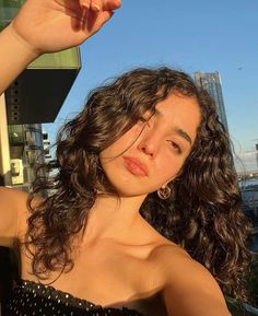 a woman with curly hair is posing for the camera