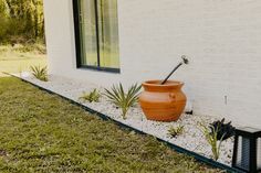 an orange pot sitting on the side of a white building next to a planter