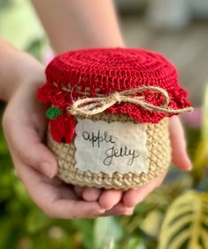 a person holding a jar with an apple jelly label on it's lid in their hands