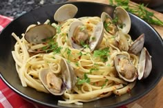 pasta with clams and parsley in a black bowl