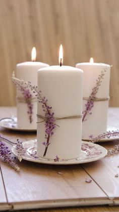 three white candles with purple flowers on them