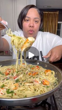 a woman is eating spaghetti with her fork and spoon in front of the stove top