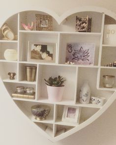 a white heart shaped shelf filled with pictures and other items