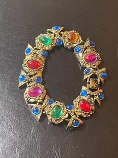 This is an exotically glamorous bracelet, unsigned designer from the 70s, in excellent vintage condition--color loss on clasps is seen. It is jeweled in dazzling "fruit salad" colors with dense resin cabs presenting a luminous, gripoix-like glow, and captures the play of light at every turn. (I have seen this described as having glass cabs, but I believe they are glass-like resin.)  The finish is an antique gold tone with raised detailing, the perfect backdrop for these vibrant cabochons, lendin Multicolor Jewel Bracelets For Party, Vintage Multicolor Bracelets For Formal Occasions, Multicolor Jewel Costume Jewelry Bracelets, Multicolor Costume Jewelry Bracelets With Jewels, Vintage Multicolor Jeweled Bracelets, Egyptian Bracelet, Vintage Runway, Yellow Bracelet, Slide Bracelet