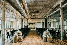 an empty room with wooden floors and tables set up for a wedding reception in front of large windows