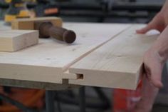 a person holding a piece of wood with a hammer in it's hand on a workbench