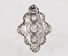 This antique circa 1910 white gold diamond ring is embellished with beautiful and delicate filigree wire work with scrolls on the sides of the ring.  The fascinating filigree eludes to a stained glass illusion encompassing 3 diamonds in the center.  The long length of this ring elongates the finger with a dazzling display of the diamonds and design.Antique Edwardian 14K White Gold Diamond Ring 14K White Gold 3 Euro Cut Diamonds = .36 carats, VS2/S1, G-HRing Size 3 (ring is sizable)Band measures 14k White Gold Diamond Ring, Antique Ring, Ring Antique, Gold Diamond Ring, White Gold Diamond Rings, Wire Work, Antique Rings, Rings Statement, White Gold Diamonds