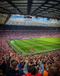 a large stadium filled with people watching a soccer game on a sunny day in the sun