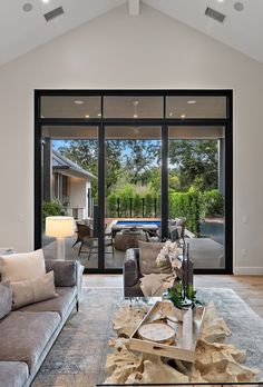 a living room filled with furniture and a large glass door leading to a swimming pool