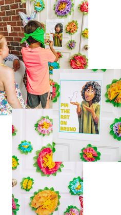 two children are looking at paper flowers on the wall and another child is pointing to them