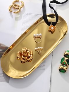 a gold tray with rings and other jewelry on it next to an open brochure