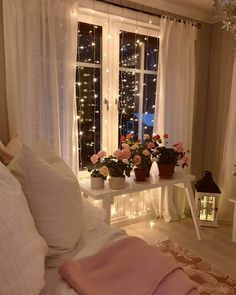 a bedroom with flowers and lights on the windowsill